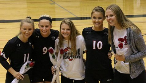 Senior volleyball players and their managers Annie Dykstra and Hanna Fisher, pose together on volleyballs Senior Night