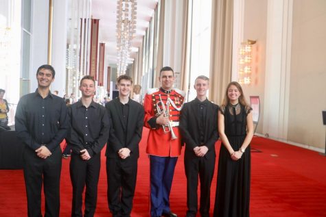 Several band students pose with director Cheryl Lee and alum, Chris Larios, who is now serving as a sergeant in the army and is a member of the US Army Band.