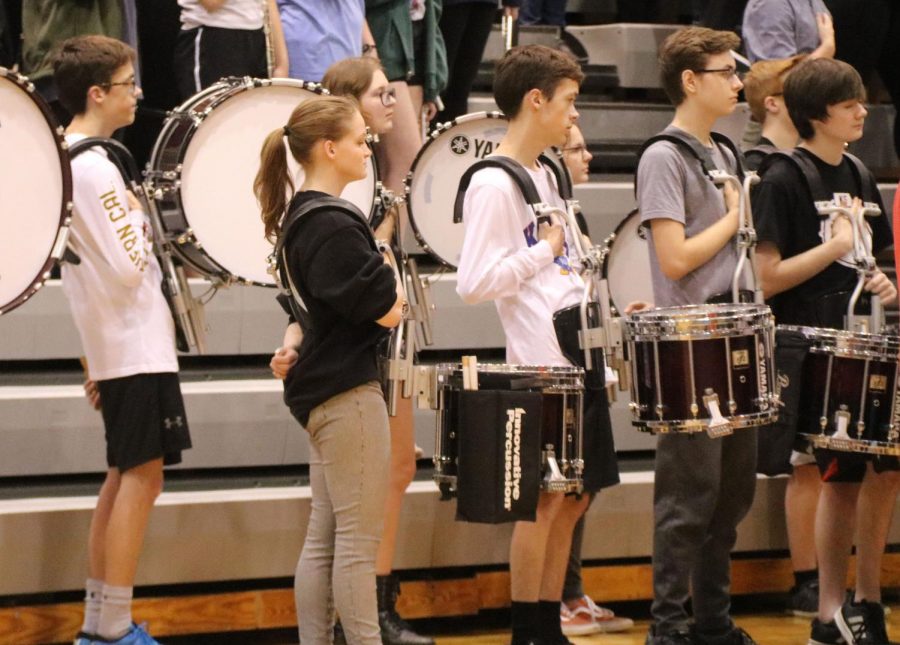 Standing at attention during the singing of the national anthem at the April 23 assembly, members of the drumline stand respectfully with the rest of the student body.