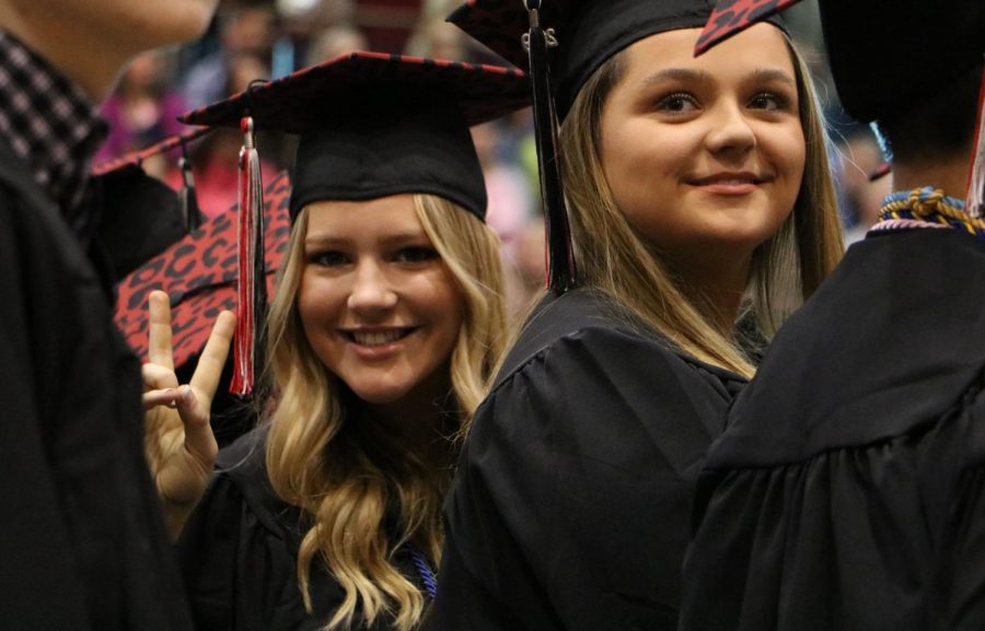 Having fun, senior Lauren Lillis gives a peace sign to the journalism photographer while Cassidy Lidgett smiles.