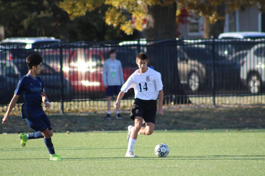 Moving away from the defender, junior Nick Edwards dribbles the ball.