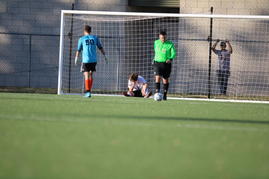 Reacting to a goal by Olathe West, senior Sam Masterson sits in the goal.
