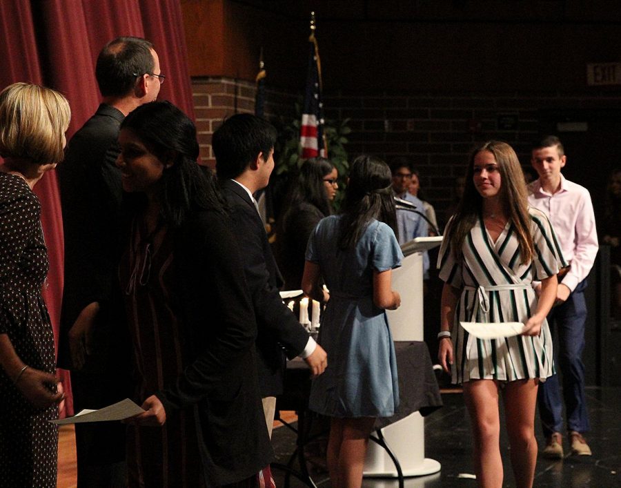 Junior Clarice Koenig crosses the stage to accept congratulations at the NHS Induction ceremony.