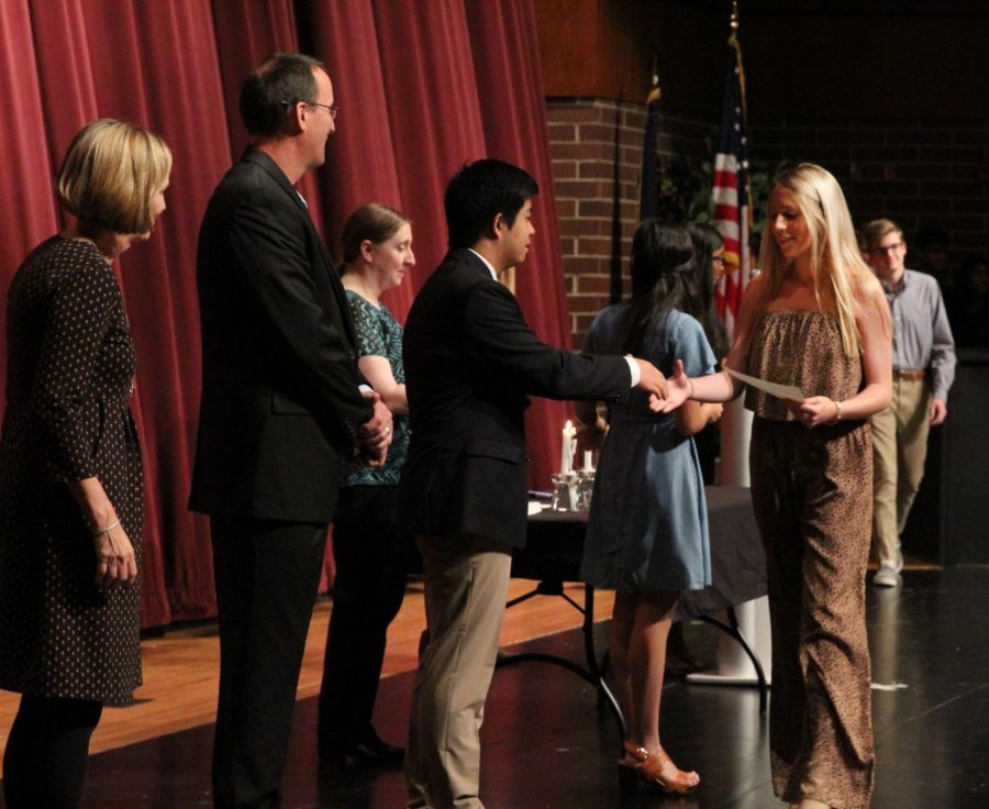 Looking at her NHS certificate, senior Katherine Lucas begins her round of congratulatory hand shakes.