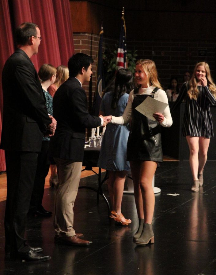 Junior Gracyn Martin starts the line of congratulations after receiving her certificate from senior Pooja Jain.