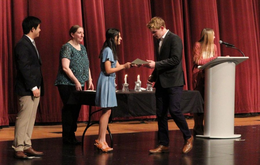 Looking closely for his name on the NHS certificate, senior Trevor Sinclair amuses senior Pooja Jain.