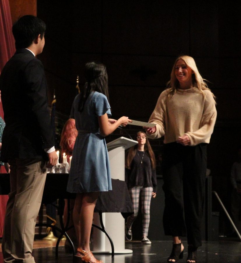 Walking across the stage to receive her certificate, junior Reese Wheeler accepts the award from Pooja Jain.