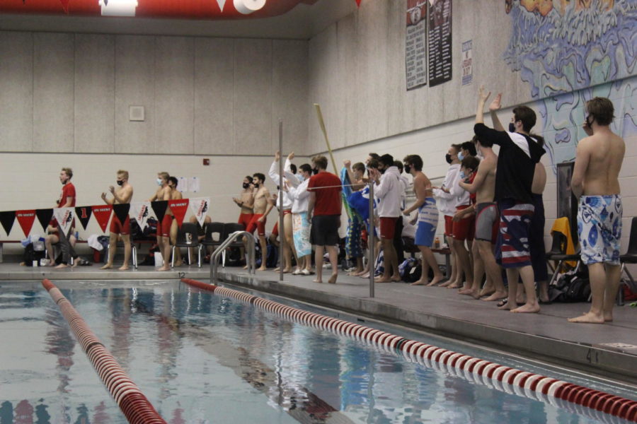 The swim team cheers on Collin Montgomery after his scored is called after taking action in his dive.