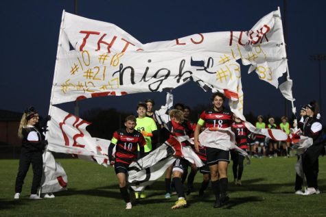 Varsity soccer breaks through banner after celebrating the seniors.
