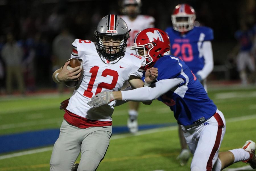 Sophomore Nick Taylor runs with ball while pushing away Miege opponent.