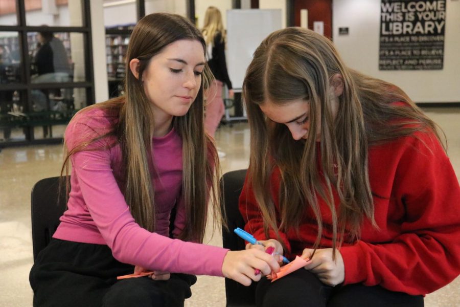 Juniors Jaylee Soule and Madison Coyne writting sticky notes for the women at blue valley west.