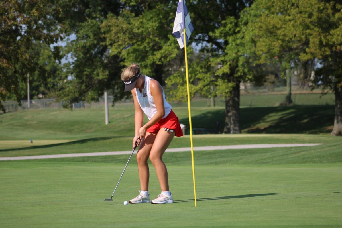 A golfer perfects her stance as she nearly finishes the current hole.