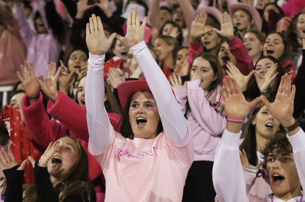 Seniors Mckenzie Glover, Isabella Huber, and Blake Kilian show their spirit at football game by wearing pink and cheering for west