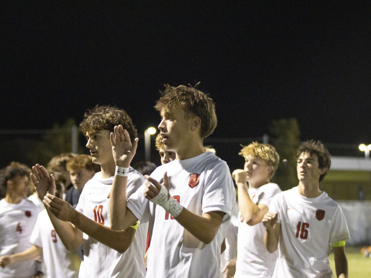 Seniors Peyton Magness and Braden Adams clap after singing the Alma Mater at the end of their game.