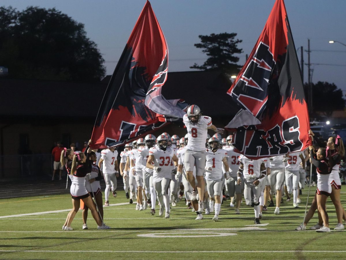 Junior Lawson McGraw runs through the west banner at the beginning of the game.