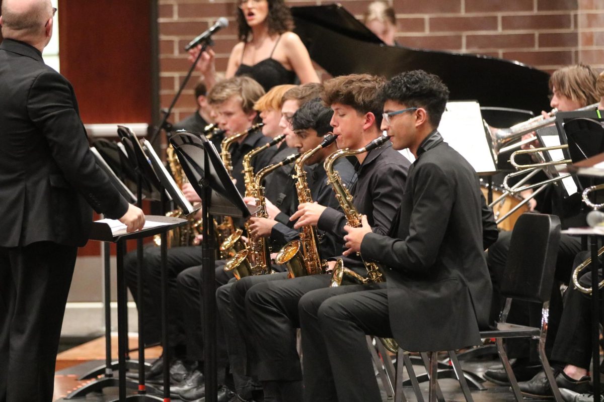 A row of boys playing the saxophone at their concert. 